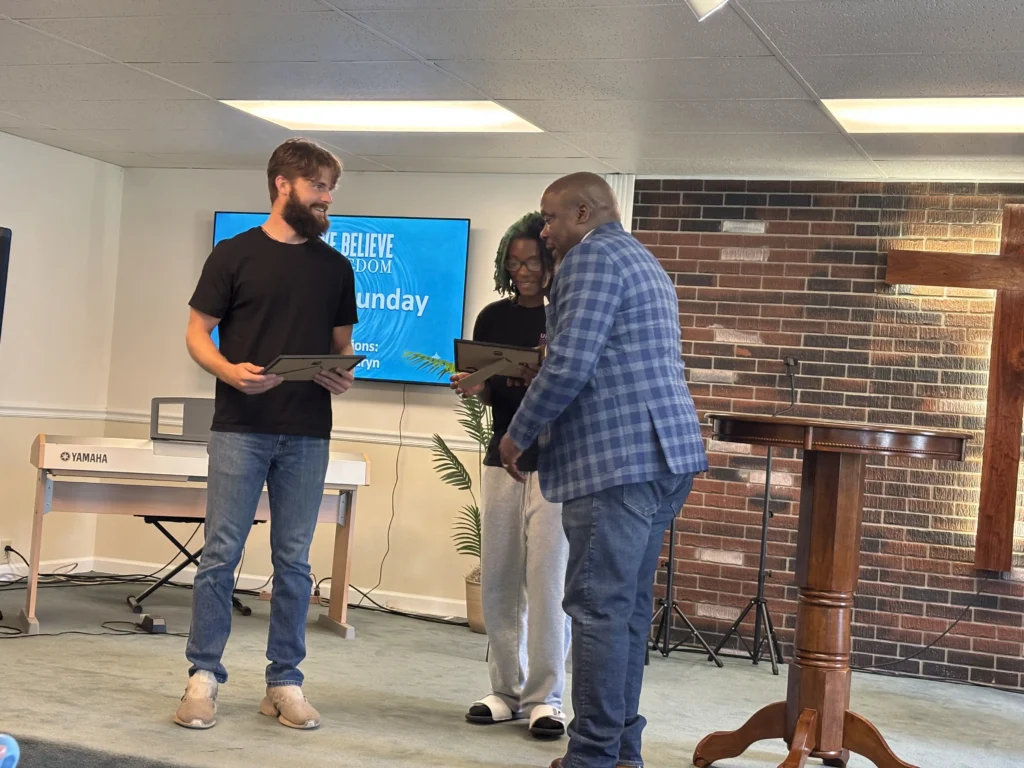 Pastor Ken handing Justin and Lauryn their baptism certificates